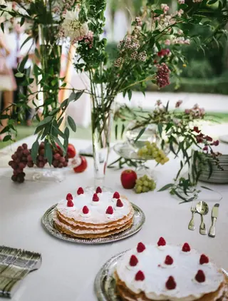 Tartas de hojaldre con nata y frambuesas en bandejas de plata sobre una mesa de postres de boda al aire libre