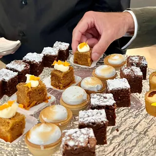 Bandeja de postres en miniatura: bizcochos con crema y flor, tartaletas de merengue y brownies