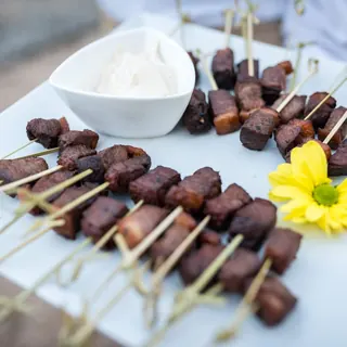 Brochetas de carne con salsa servidas en bandeja durante el cóctel de la boda