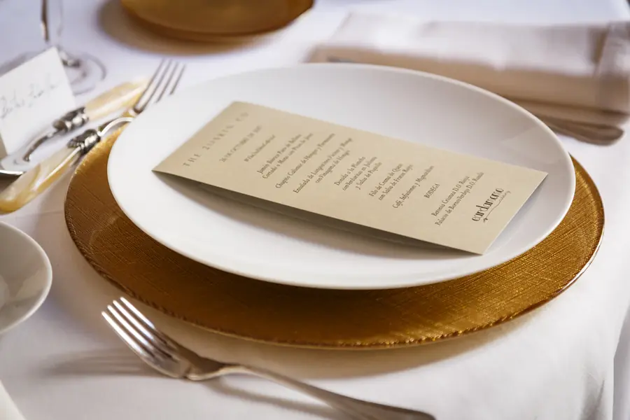 Mesa vestida para una cena de gala con minuta impresa, bajoplato de cristal dorado y cubiertos de plata