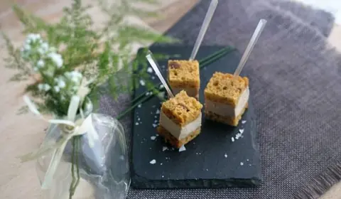 Tres milhojas de foie en pan de higos con escamas de sal, pinchados en palillos sobre una pizarra