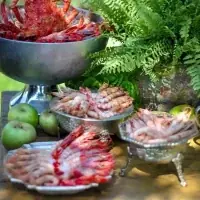 Centollo y carabineros en copa de plata con fuentes de gambas sobre mesa de madera en el cóctel de una boda