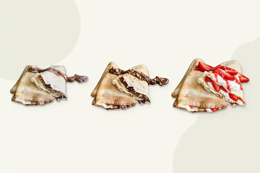 Tres crepes doblados en cuatro rellenos de dulce de leche, crema de cacao y fresas con nata