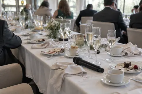 Mesa de cena de empresa tras el postre con copas de cava y un micrófono preparado para el discurso
