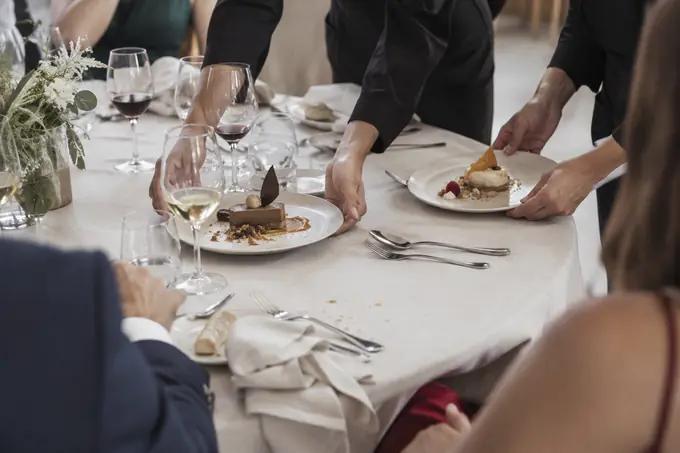 Camareros sirviendo el postre en una cena de empresa antes del discurso y el brindis