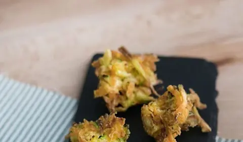 Buñuelos crujientes de verduras ralladas, con zanahoria y calabacín, sobre una pizarra y un paño de rayas