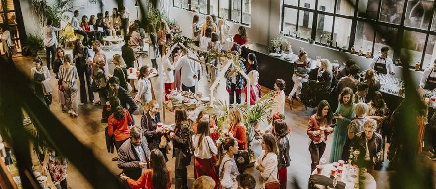 Evento de empresa en un espacio diáfano con invitados de pie, mesas de cóctel y barra de bebidas en Madrid