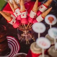 Brochetas de nubes y fresa decoradas como payasos con gorro de barquillo en una mesa dulce para fiestas infantiles
