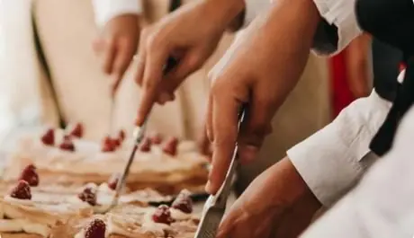 Camareros de Cardamomo Catering cortando tartas de hojaldre con nata y frambuesas durante el servicio de una boda