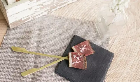Dos bocados de tataki de solomillo, rojo por dentro y sellado por fuera, con escamas de sal en palillos sobre pizarra