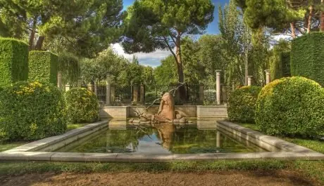 Estanque con escultura de piedra rodeado de setos y pinos en Los Jardines de Celio Rodríguez, espacio para bodas