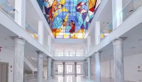 Gran vidriera de colores sobre el salón con columnas de mármol del Palacio de Neptuno, espacio para eventos en Madrid