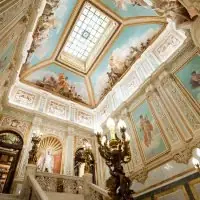 Escalera del Palacio de Santoña con techos pintados al fresco, vidriera cenital y candelabros dorados, en Madrid