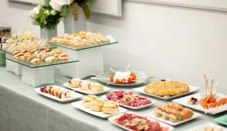 Bufé de picoteo con tortilla de patata, jamón, sándwiches, brochetas y mini bocadillos para eventos de empresa