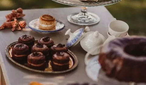 Tarta semidesnuda con naranja deshidratada y flores, magdalenas de chocolate, bundt cakes y un juego de té en el jardín